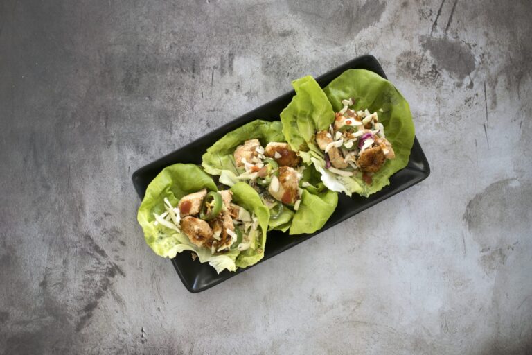 High angle view of lettuce wraps with vegetables and meat in a black plate on the table
