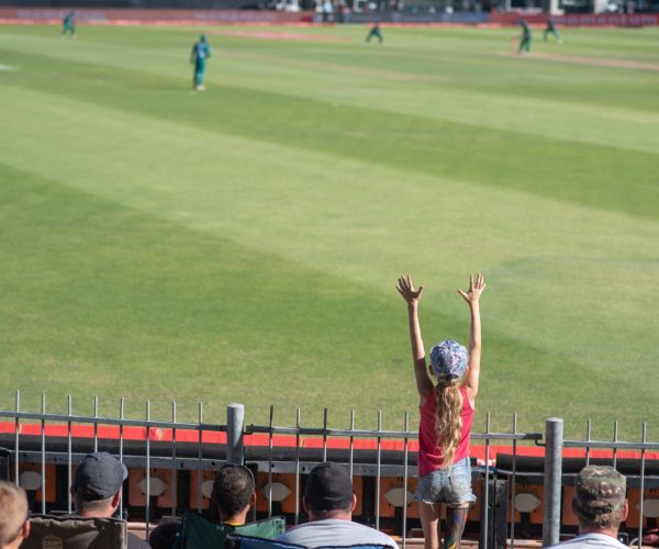 Young fan throwing up her hands in excitement at cricket match